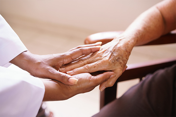 Young nurse's hands grasping older patient hand